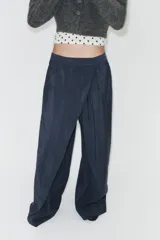 Pantalón de tiro alto con diseño cruzado tipo pareo en el frente, pernera ancha y caída fluida.