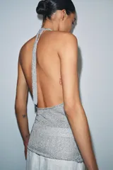 Top halter de punto con hilo metalizado, color plateado, con escote pronunciado y tirantes para anudar al cuello.