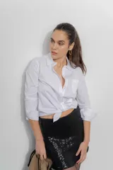 Camisa de corte clásico confeccionada en popelina blanca, con cuello camisero, cierre frontal de botones, bolsillo en el pecho y mangas largas con puños abotonados.