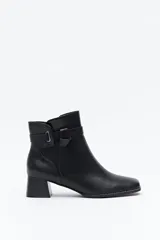 Bota corta de caña baja color negro, con puntera cuadrada, taco medio y tira decorativa con hebilla metálica en el lateral.