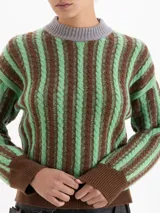 Sweater de punto con diseño de ochos y rayas verticales en color rojo. Presenta cuello redondo, puños y cintura en contraste de color marrón oscuro.