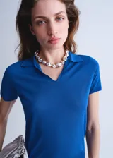 Buzo de punto color azul, con cuello polo y manga corta, de diseño recto.