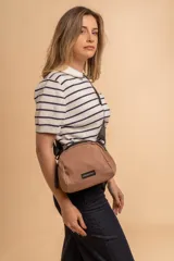 Bandolera pequeña de diseño moderno, confeccionada en tafeta liviana y resistente. Cuenta con cierre superior, correa ancha ajustable y logo frontal de la marca.