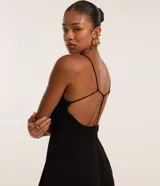 Mono negro de sastrería con breteles finos ajustables, escote en V con nudo y detalle trenzado en la espalda. Pantalón palazzo.