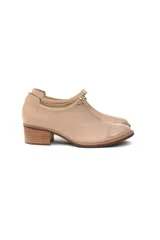 Zapatos de cuero color crema, con diseño cerrado tipo botineta de caña baja, puntera reforzada en charol y taco cuadrado de madera de 5 cm. Presenta un detalle de hebilla metálica dorada en el empeine.