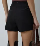 Short pollera corto de sastrería, con diseño cruzado redondeado y cierre de cremallera en la espalda.