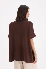 Saco de punto color chocolate, con cuello redondo, cierre frontal de tres botones y mangas cortas con dobladillo.