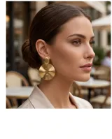 Caravanas de diseño circular con acabado en tono dorado, compuestas por un elemento superior ovalado y un disco inferior de gran tamaño con superficie cóncava.