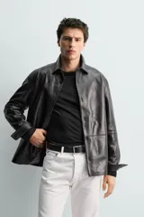 Sobrecamisa de corte regular confeccionada en piel napa negra, con cuello solapa, cierre frontal de botones y mangas largas con puños abotonados.