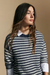 Sweater de punto con diseño de rayas horizontales en tonos tierra, con textura acanalada y cuello redondo. Presenta un corte relajado y mangas largas.
