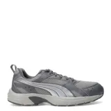 Championes Puma Milenio Tech Lt de color gris, con diseño de inspiración retro, parte superior de malla transpirable y detalles superpuestos en material sintético con la característica franja lateral de la marca en tono plateado. Cuenta con cordones grises y suela de goma amortiguada.