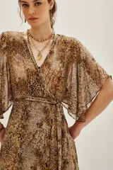 Vestido largo de estilo envolvente con estampado animal print, confeccionado en tejido fluido y ligero. Presenta escote en V, mangas tipo kimono amplias y lazo ajustable en la cintura que permite entallar la silueta. Incluye una abertura frontal en la falda.