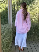 Camisa celeste a rayas verticales blancas, de corte holgado, manga larga y cuello camisero.