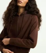 Saco femenino de algodón con capucha ajustable, mangas largas, cierre frontal con cremallera y bolsillos laterales.