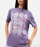 Remera de algodón color lila con efecto lavado, cuello redondo y mangas cortas. Presenta estampa frontal licenciada de The Rolling Stones con múltiples repeticiones del icónico logo de la lengua y detalles metalizados.