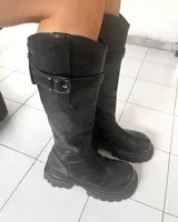 Botas bucaneras negras de cuero sintético, con caña alta, hebilla decorativa en el lateral y suela track.