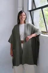 Poncho abierto de tejido de punto color verde oliva, con mangas cortas tipo kimono y bolsillos frontales aplicados.