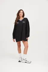 Camiseta negra oversize de manga larga con cuello en V blanco y logo en el pecho.