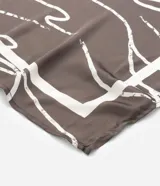 Pañuelo cuadrado de satén color marrón con estampado abstracto en tonos beige.