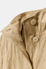 Chaqueta de efecto ante con cuello alto, manga larga y cierre frontal oculto por solapa con botones. Cuenta con bolsillos delanteros de plastrón con solapa y cintura ajustable con cordones.