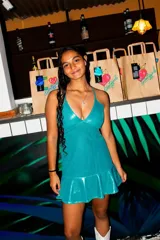 Vestido midi de fiesta color fucsia con acabado brillante, compuesto por un top con escote en V y tirantes finos, y una falda con aberturas laterales en la cintura.