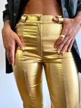 Pantalón dorado de tiro alto, corte ajustado hasta la rodilla y acampanado con aberturas en el ruedo.