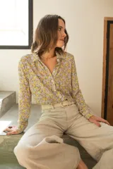 Camisa de seda de corte clásico con cuello camisero, cierre frontal de botones y mangas largas con puños. Presenta un estampado floral multicolor con tonos pasteles sobre fondo claro.