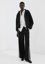Pantalón negro de corte recto con franjas blancas laterales a lo largo de las piernas.