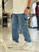 Pantalón cargo de jean azul con múltiples bolsillos en los laterales y diseño holgado.