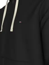 Buzo negro de felpa de algodón con capucha y cordón ajustable, cierre de cremallera frontal, bolsillos tipo canguro y logo de Tommy Hilfiger bordado en el pecho.