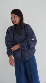 Campera puffer azul marino con diseño matelaseado de rombos, cuello mao de cuero sintético negro, cierre frontal con cremallera y mangas largas abullonadas con puños elásticos.