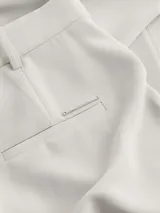 Pantalón largo de vestir color gris claro, de sarga de poliéster reciclado, con pierna ancha, talle medio, detalle de pliegue prensado delante y detrás, bragueta con cremallera con cierre de corchete, bolsillos con ranura y bolsillos traseros ribeteados.