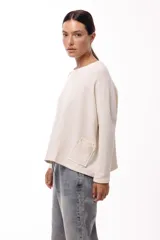 Remera de silueta relajada, confeccionada en tejido de punto, con cuello redondo, mangas largas y un bolsillo aplicado en el frente.