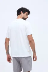 Remera blanca de manga corta con cuello redondo y estampa frontal de estilo vintage con texto inscripto.