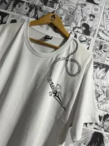 Remera blanca de manga corta con estampado de vinilo textil de una cadena con una daga en el pecho.