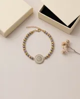 Pulsera de acero con baño de oro, compuesta por esferas metálicas en tonos dorados y plateados, con un dije central redondo decorado con cristales multicolor.