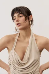 Top negro con diseño cruzado tipo halter, escote pronunciado y fruncido lateral.