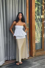 Vestido midi de diseño strapless con escote recto. Presenta un cuerpo superior blanco con textura fruncida y una falda inferior en tono beige con caída fluida.