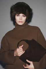 Bolso formato mini shopper confeccionado en piel de ante color topo. Cuenta con doble asa de mano, asa bandolera extraíble, cierre mediante botón imantado y bolsillo interior con cremallera.