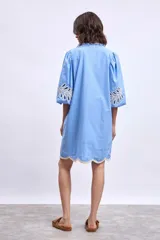 Vestido blanco de lino con escote en V, mangas cortas abullonadas y bordados florales en beige en mangas y ruedo.