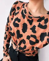 Remera color camel con estampado animal print negro, de mangas largas abullonadas y nudo en la parte delantera.