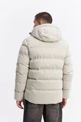 Campera puffer con capucha, diseño acolchado, cierre frontal y bolsillos laterales. Presenta un interior en contraste de color verde oliva.