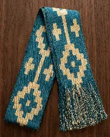 Faja de algodón tejida en telar de mano con trama apretada y diseño geométrico en color turquesa y beige, con flecos en los extremos.