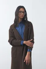 Cardigan de tejido de punto gris, con silueta larga, frente abierto, solapas clásicas y bolsillos aplicados en los laterales.