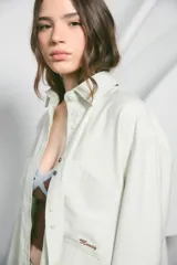 Camisa oversize color marrón, confeccionada en twill, con bolsillos irregulares y bordado 'munay' a contratono.