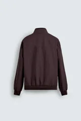 Cazadora azul marino de corte regular fit, confeccionada en tejido técnico repelente al agua. Presenta cuello subido, manga larga, bolsillos de vivo en cadera, bolsillo interior y acabados en rib en puños y bajo. Cierre frontal de cremallera oculta por solapa con botones a presión.