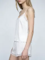 Conjunto de pijama compuesto por una musculosa de breteles finos con detalle de encaje en el escote y un short con terminación de encaje en el ruedo.