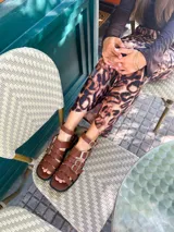 Sandalias planas de cuero color marrón, con tiras anchas y hebillas plateadas.