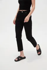 Pantalón jean de tiro alto y corte recto, color blanco, con bolsillos laterales y traseros, y terminación desmechada en los tobillos.
