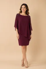 Vestido corto de jersey con capa superpuesta de gasa en color borgoña. La capa presenta un diseño irregular y aplicaciones de pedrería dorada en los hombros.